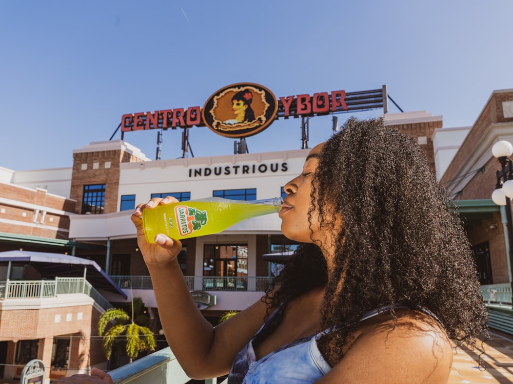 woman in white and blue floral tank top holding yellow plastic cup