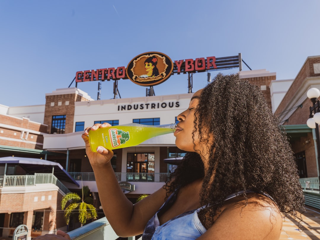 woman in white and blue floral tank top holding yellow plastic cup,