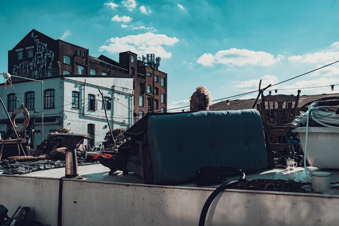 man in black jacket sitting on car hood during daytime