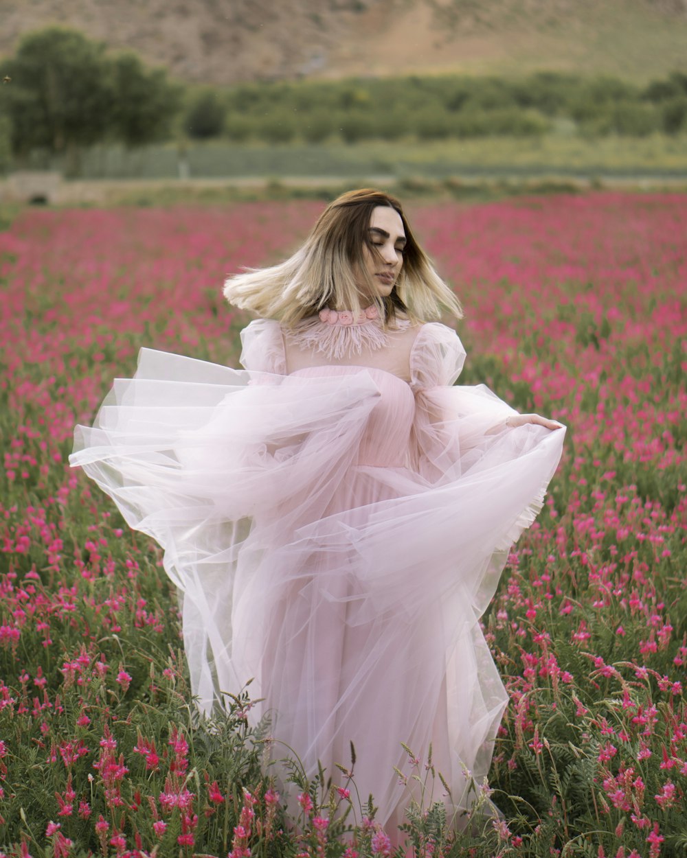 woman in white dress sitting on red flower field during daytime