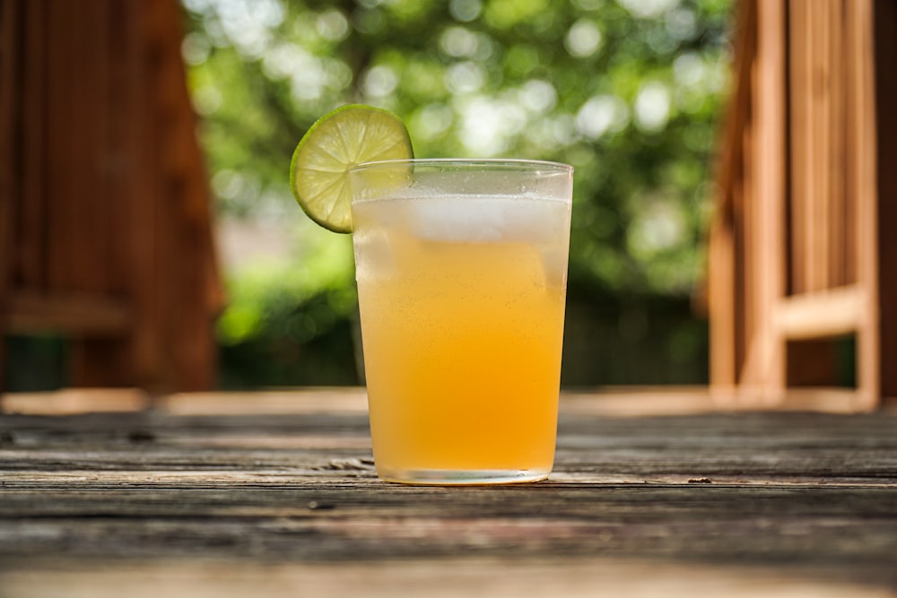 clear drinking glass with yellow liquid and sliced lemon