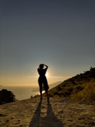 A silhouette of a young person standing on a hill, watching the sunrise.