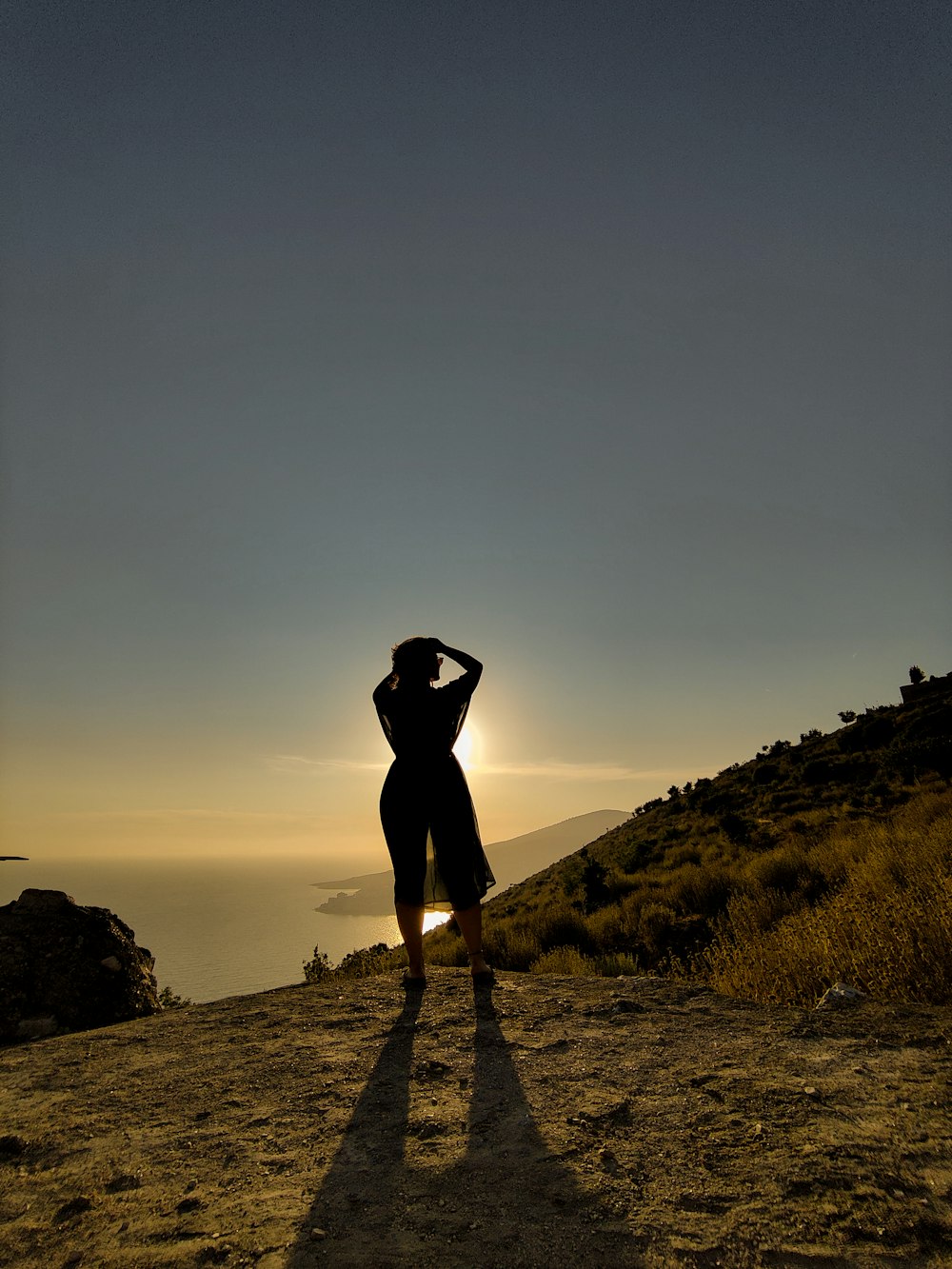 silhouette of person standing on rock during sunset