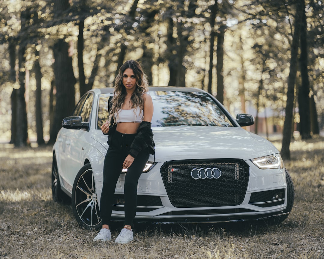 woman in black tank top and black pants sitting on black audi car