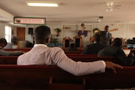man in white dress shirt sitting on brown wooden bench