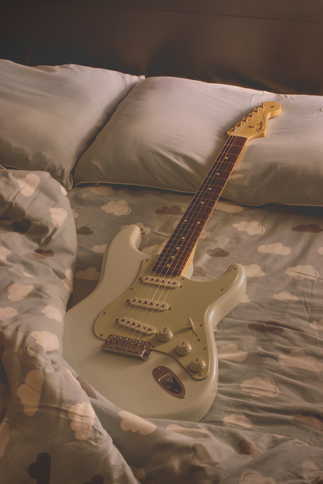 white and brown stratocaster electric guitar on white textile