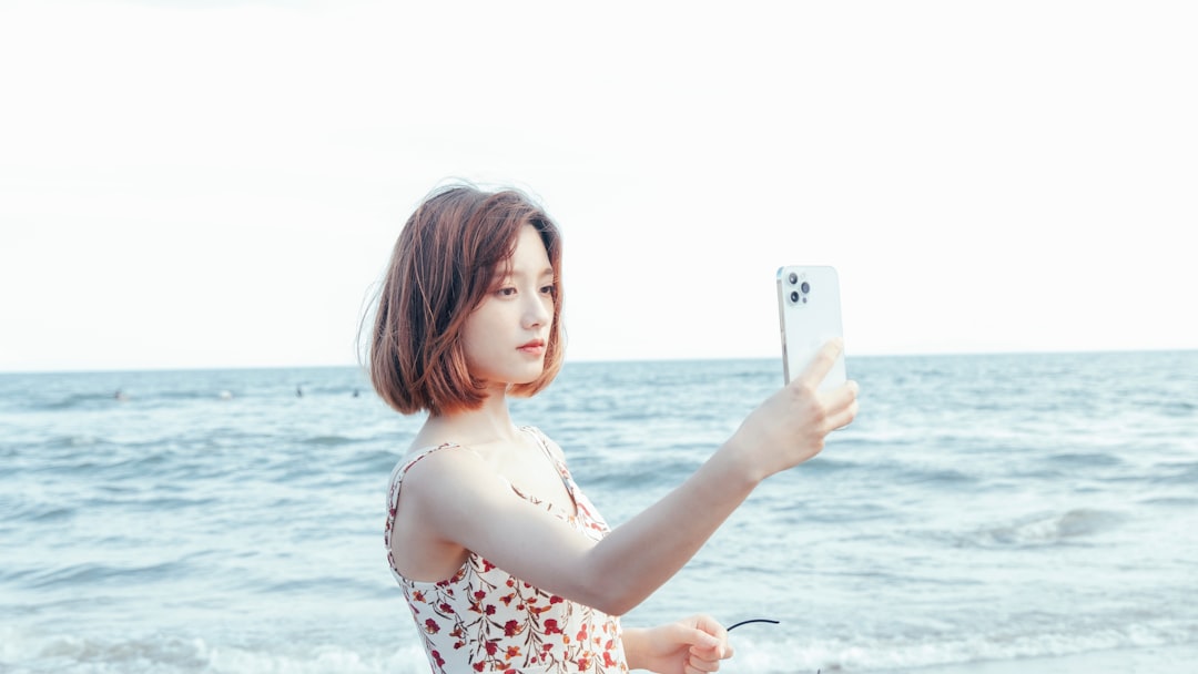 woman in white red and black floral tank top holding white smartphone