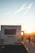 A happy couple checking their RV’s engine together at a scenic campsite during golden hour.