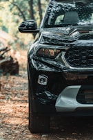 Close-up of a shiny black SUV's front grille under natural light.