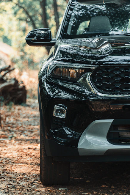 Side view of a shiny white SUV freshly polished with reflection of trees on the surface