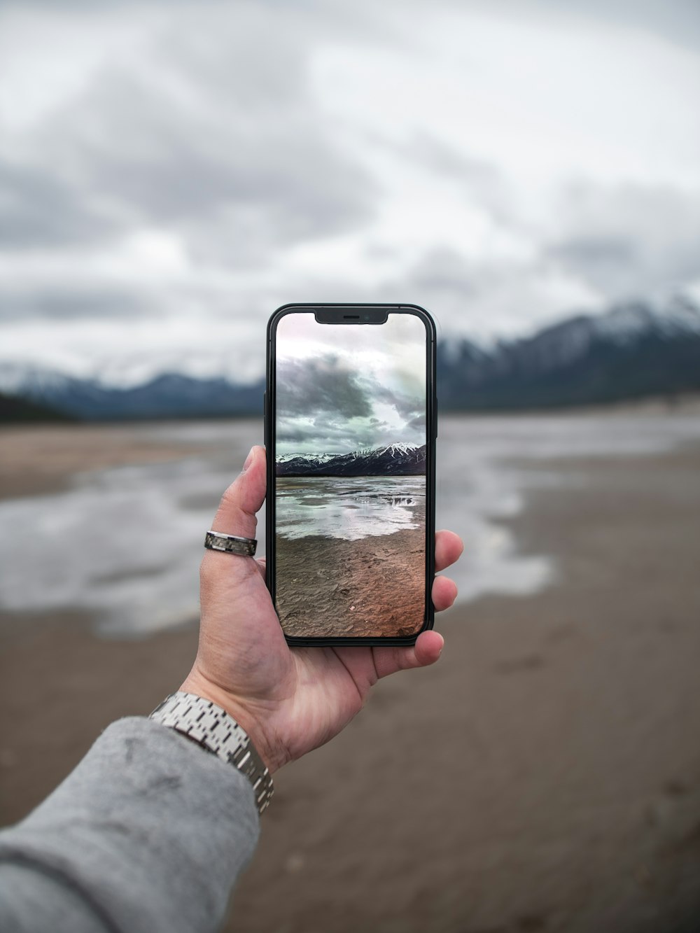 Person, die das silberne iPhone 6 hält, fotografiert tagsüber ein Gewässer