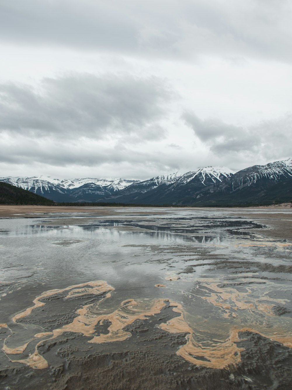 lake near mountain under cloudy sky during daytime