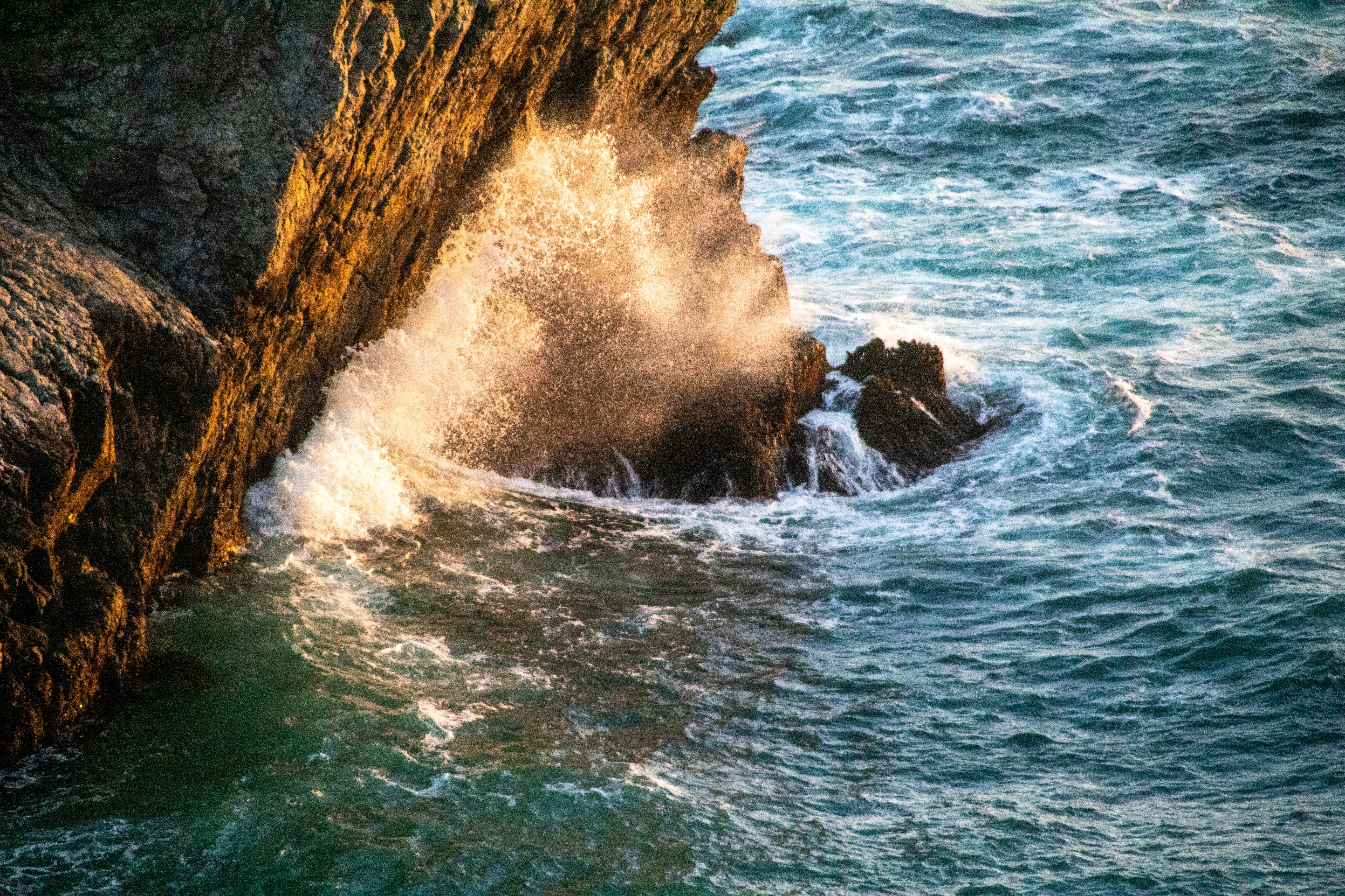 ocean waves crashing on brown rock formation during daytime