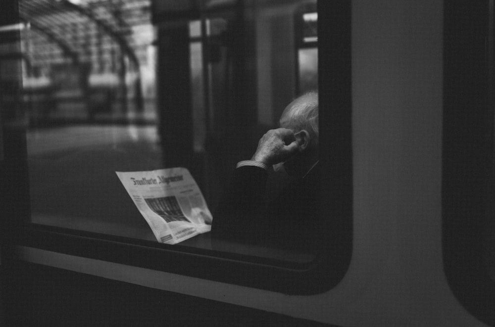 a black and white photo of a man reading a newspaper