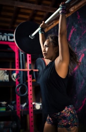 woman in black tank top holding black dumbbell