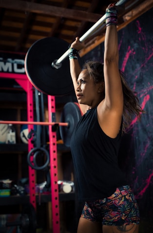 woman in black tank top holding black dumbbell