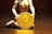 A figurine kneels and holds a large gold coin featuring the Ethereum logo and text. The background is dark, highlighting the coin's metallic sheen.