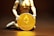 A figurine kneels and holds a large gold coin featuring the Ethereum logo and text. The background is dark, highlighting the coin's metallic sheen.