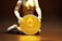 A figurine kneels and holds a large gold coin featuring the Ethereum logo and text. The background is dark, highlighting the coin's metallic sheen.