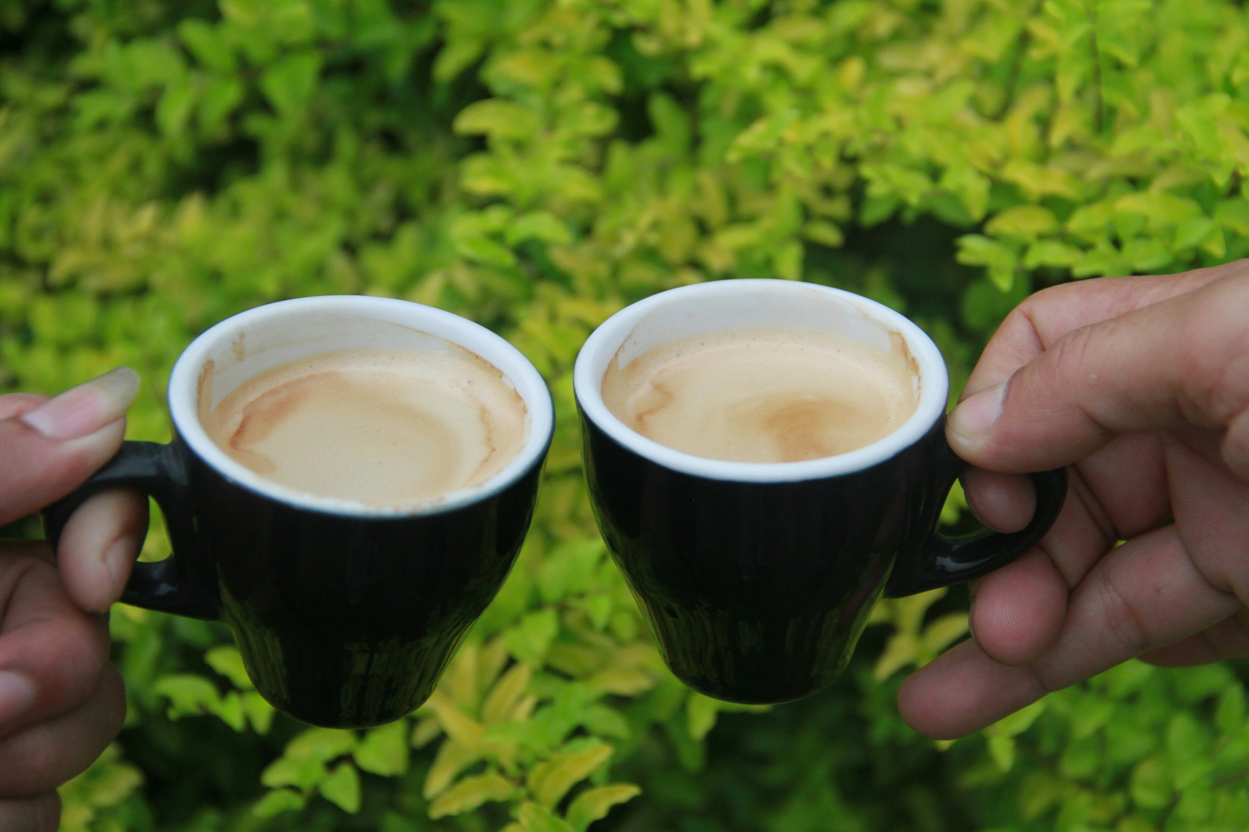 person holding black ceramic mug with brown liquid