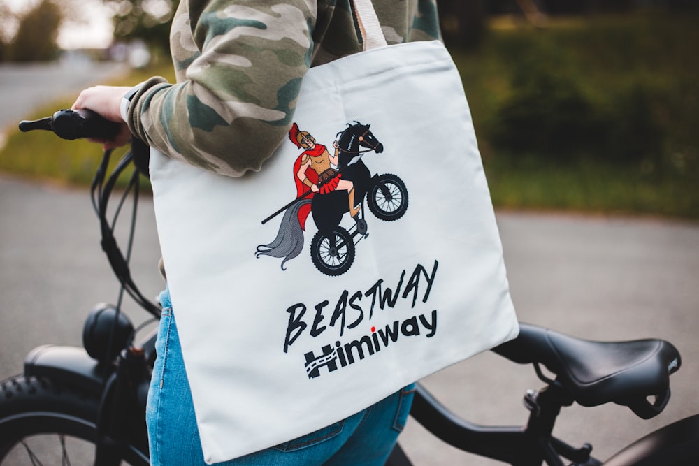 person in gray jacket holding white and black tote bag