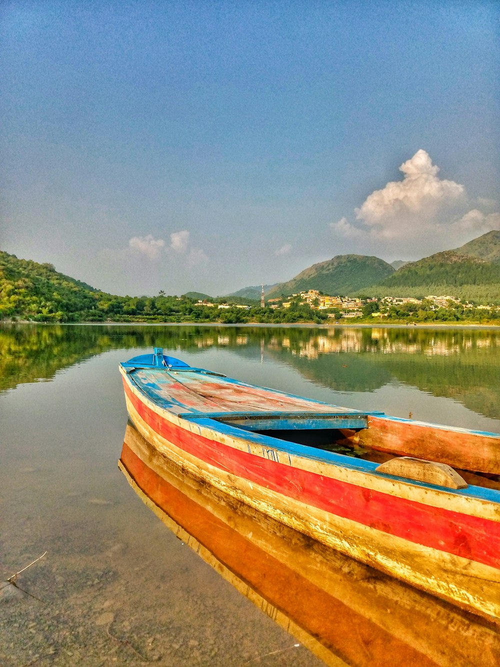 red and blue boat on shore during daytime