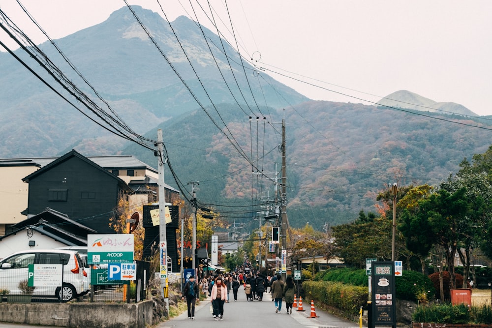 昼間、建物や山の近くの通りを歩く人々