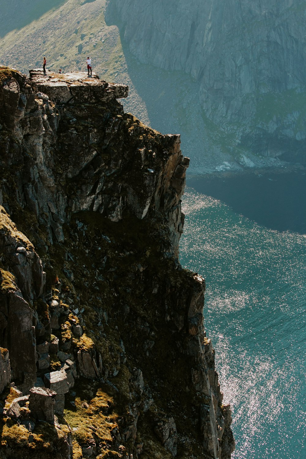 brown rocky mountain beside blue sea during daytime