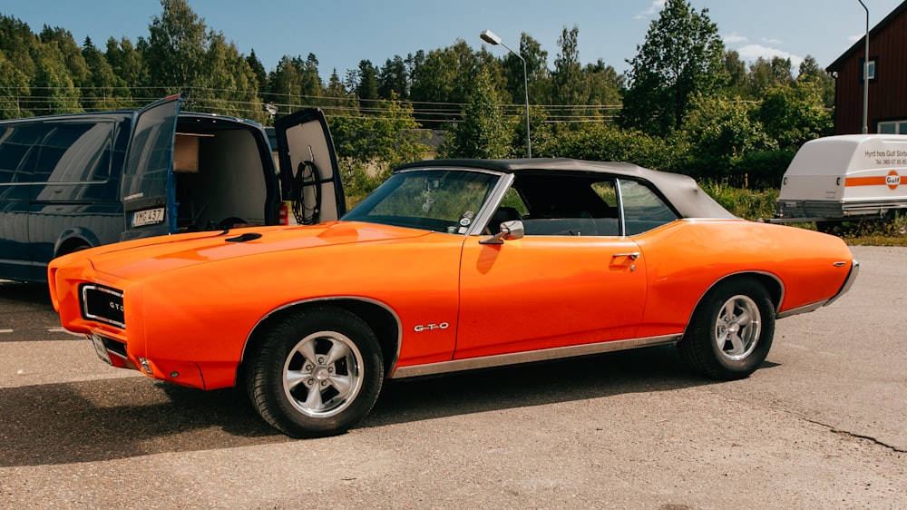 orange chevrolet convertible parked on gray asphalt road during daytime