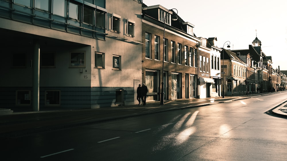 personnes marchant sur le trottoir près d’un bâtiment pendant la journée