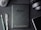 A flat lay composition on a dark textured surface includes a black Amazon Kindle device, surrounded by a pencil, a pen, a computer mouse, a pair of headphones, and the corner of a smartphone. The Kindle's back is centered and showcases the Amazon logo.