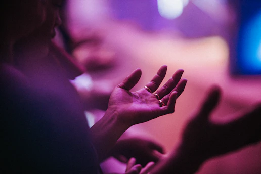 A serene image of hands gently radiating soft purple and gold energy light.