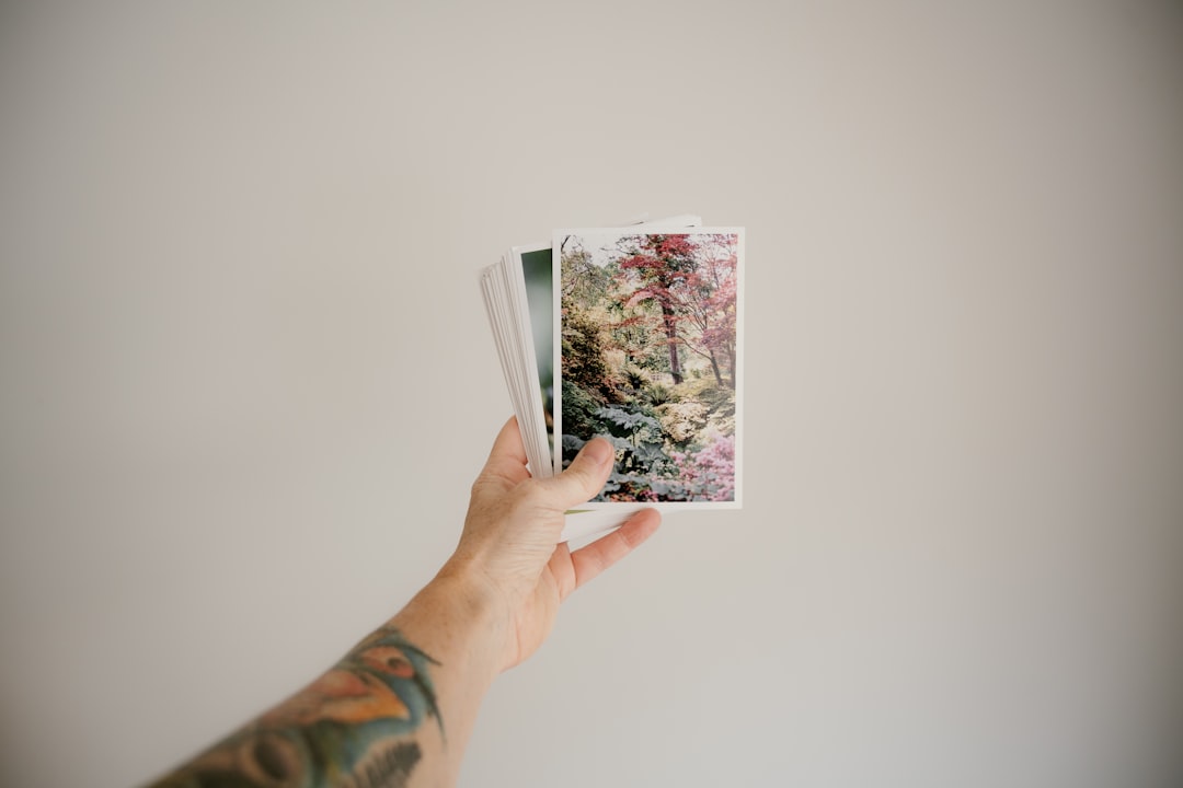 person holding white and pink floral card