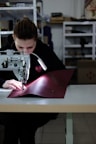 boy in black jacket using sewing machine