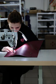 Craftsman hand sewing a vibrant pet hoodie with colorful threads.