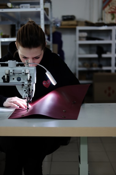 Photo of a tailor carefully stitching a company uniform in a bright workshop