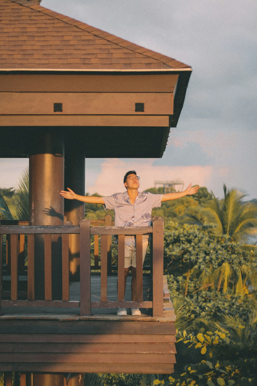 woman in white shirt standing on brown wooden bridge