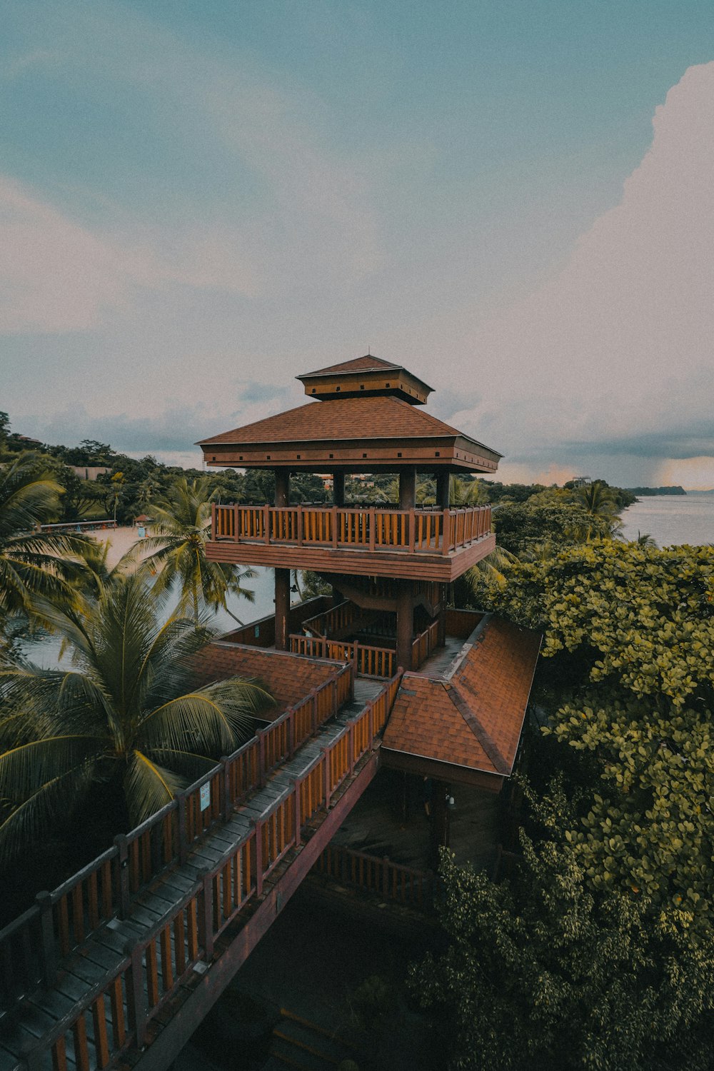 brown and white wooden house near green trees under white clouds during daytime