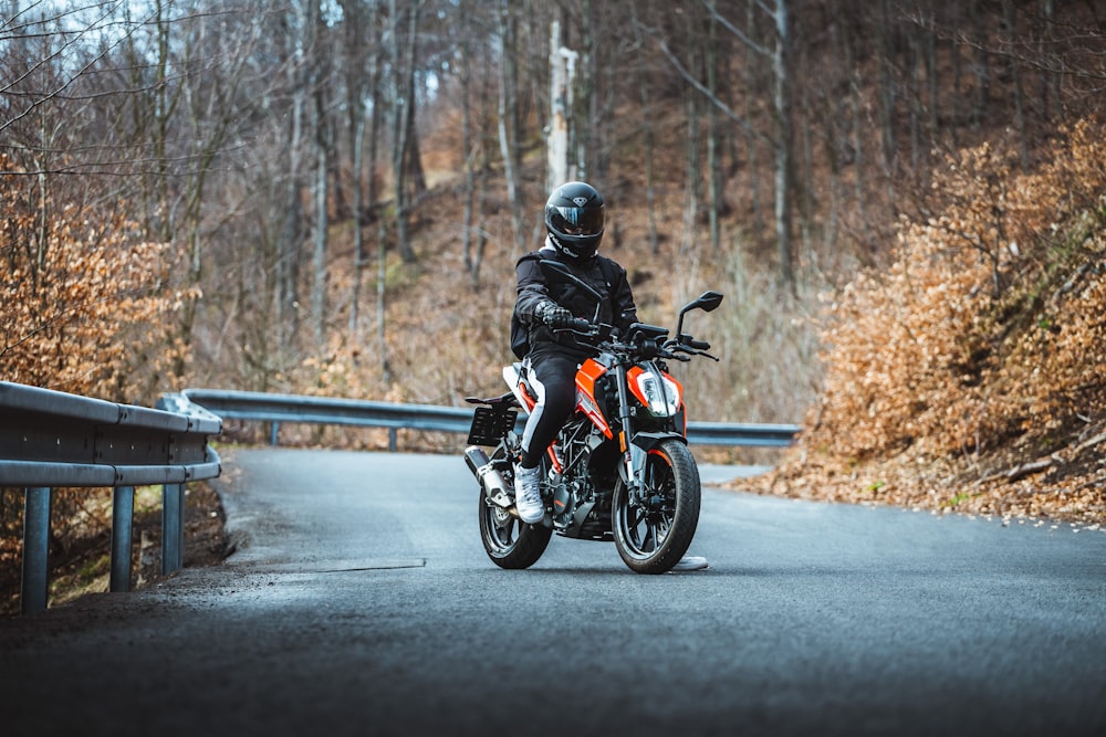 uomo in casco da motociclista nero che guida la moto su strada durante il giorno