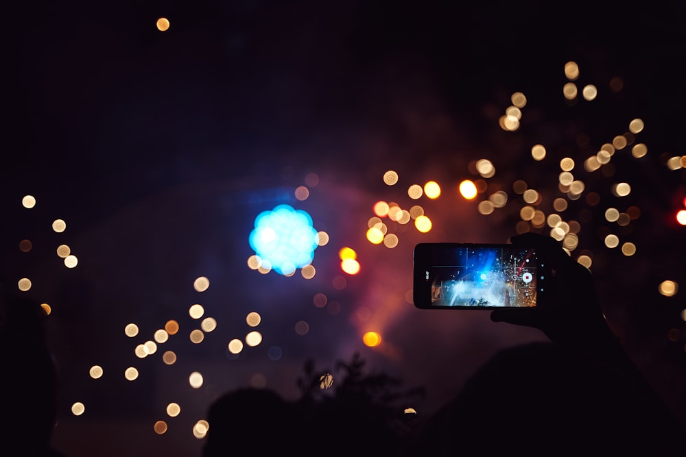 black smartphone taking a photo of a people during night time