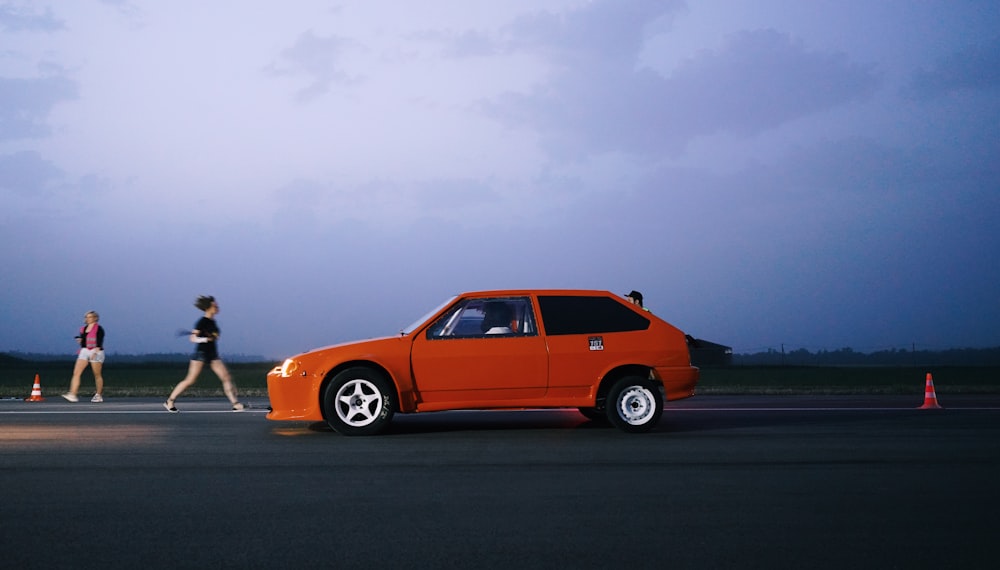 orange 5 door hatchback on road during daytime