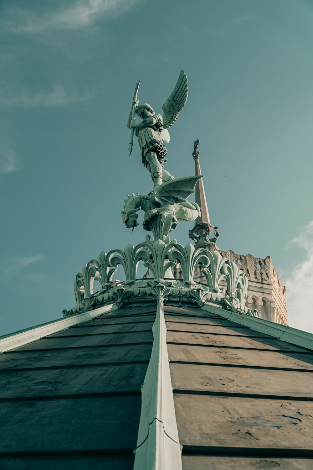 Statue verte et blanche de l’homme au sommet du bâtiment