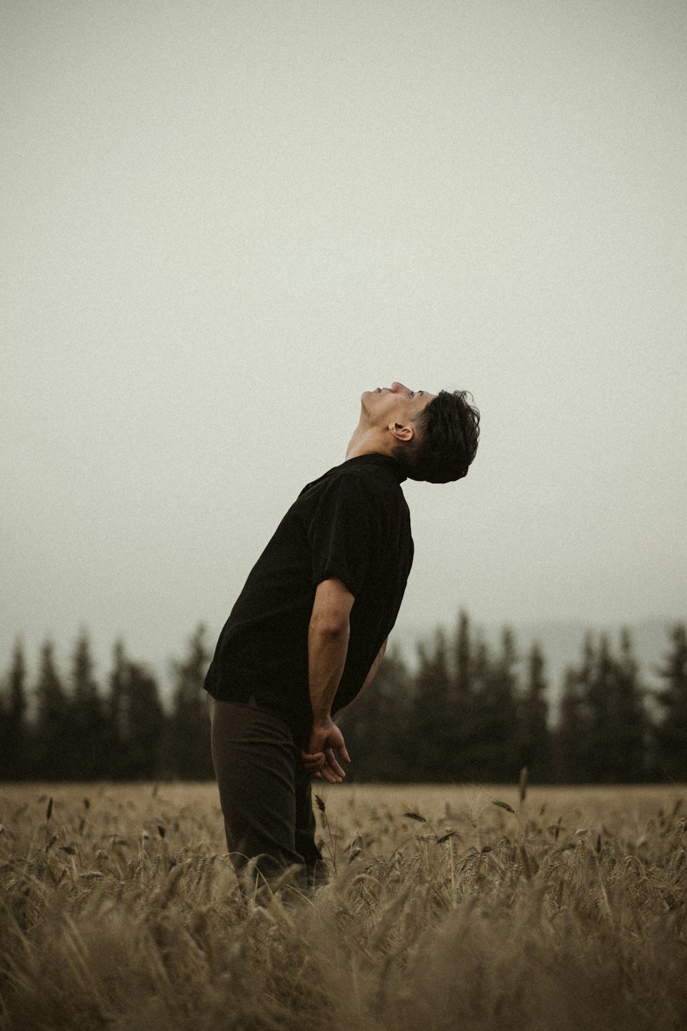 man in black crew neck t-shirt and gray pants standing on brown field during daytime