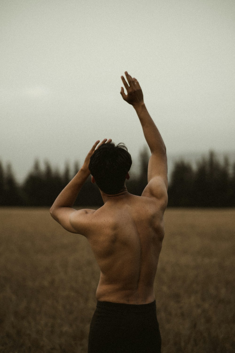 topless man raising his hands