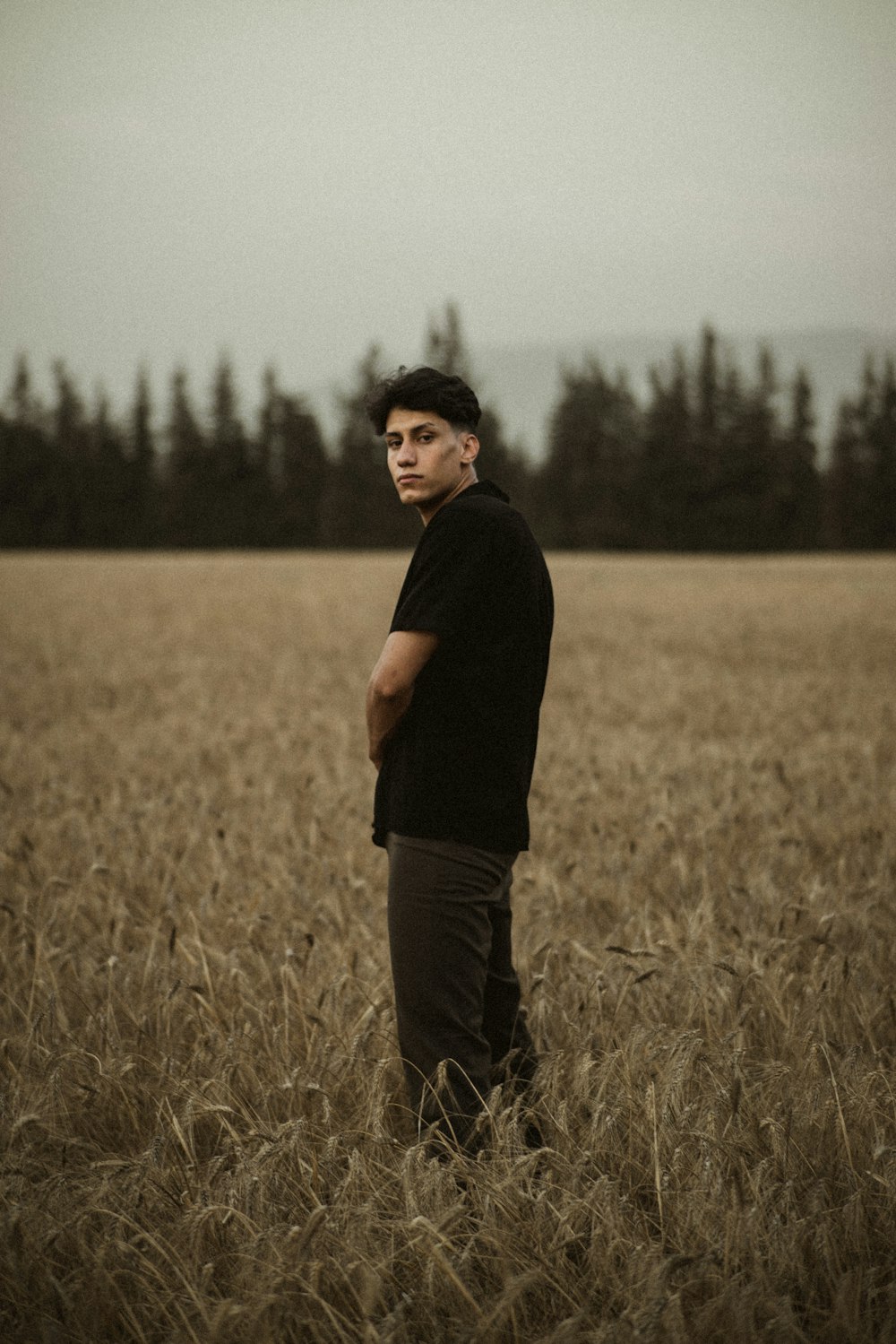 man in black t-shirt standing on brown grass field during daytime
