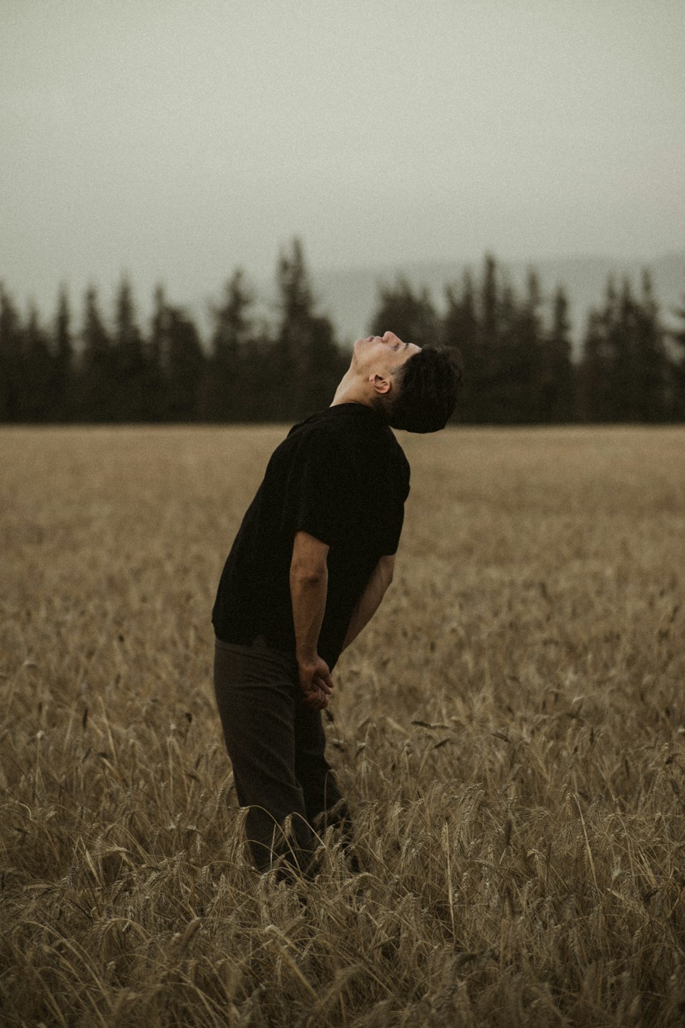 man in black t-shirt and black pants standing on brown grass field during daytime