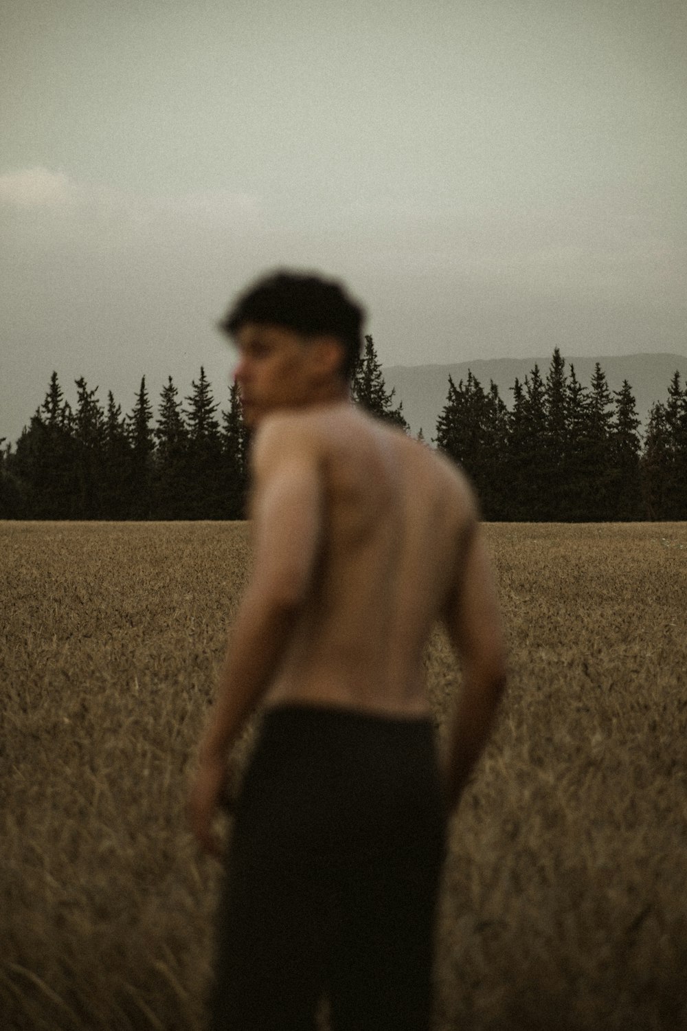 homme aux seins nus en short noir debout sur un champ d’herbe brune pendant la journée