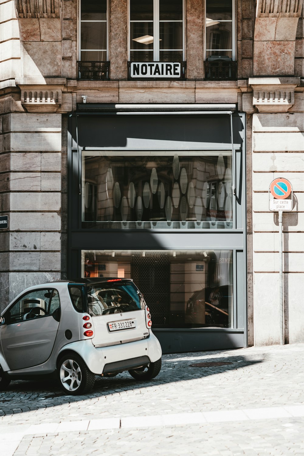 white 5 door hatchback parked beside brown brick building during daytime