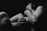 A black and white artistic photograph of a person with bare skin, featuring a dramatic play of shadows and light. The figure's pose is expressive and conveys a sense of introspection or emotion.