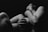 A black and white artistic photograph of a person with bare skin, featuring a dramatic play of shadows and light. The figure's pose is expressive and conveys a sense of introspection or emotion.
